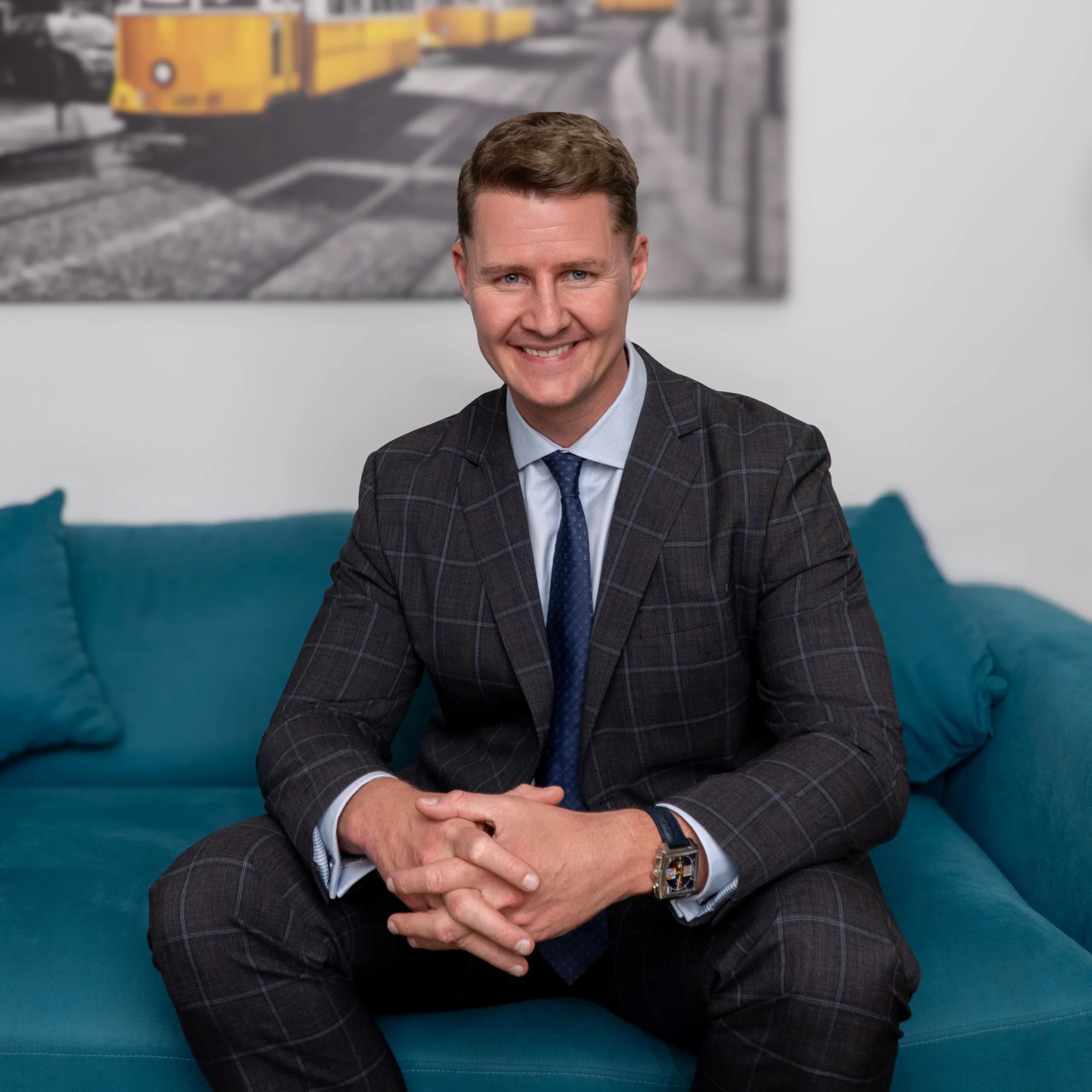 Jason Swan, owner of JS Prive, seated in a professional setting wearing a dark checkered suit and blue tie.